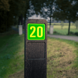 Poteau de numéro de maison avec panneau vert réfléchissant fluorescent